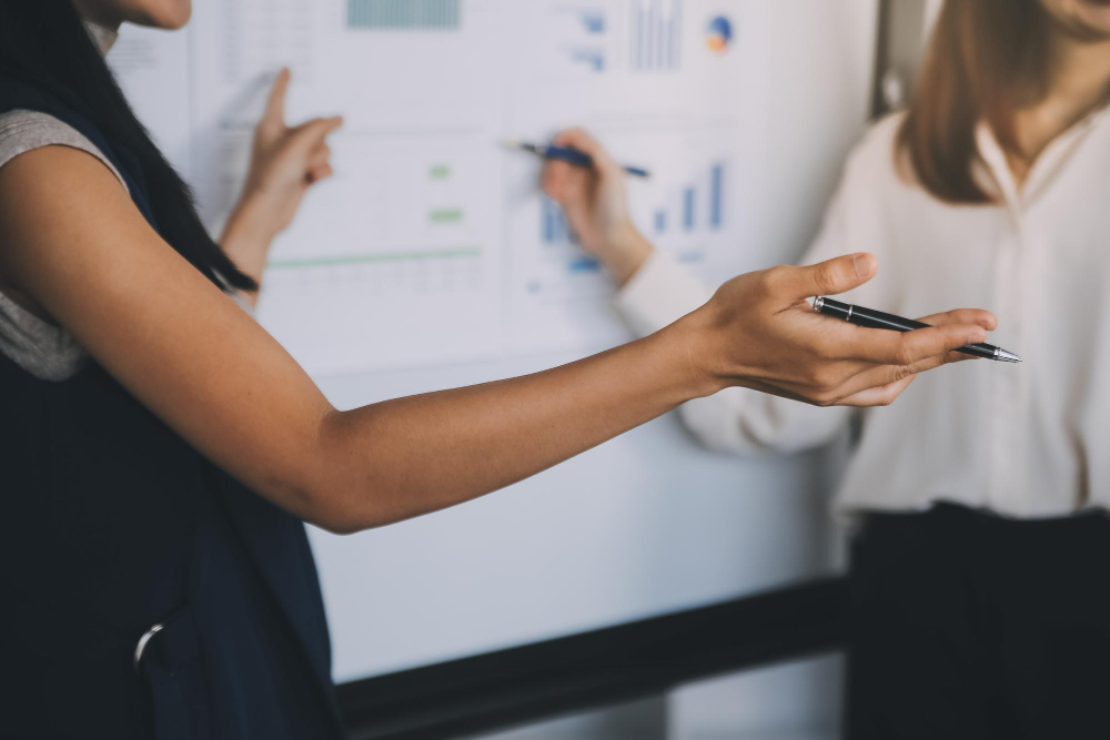 An advisor walking a colleague through charts on a whiteboard